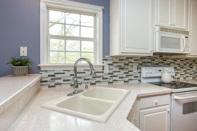 kitchen featuring white appliances, a sink, white cabinetry, decorative backsplash, and light countertops