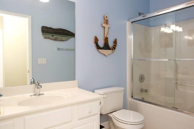 bathroom featuring toilet, combined bath / shower with glass door, and vanity