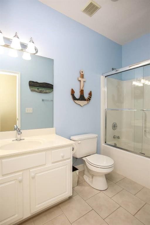 bathroom featuring tile patterned flooring, toilet, bath / shower combo with glass door, and vanity