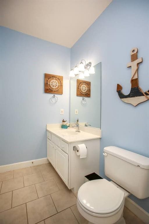 half bathroom with toilet, vanity, tile patterned floors, and baseboards