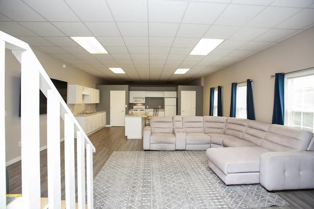 living room with wood finished floors and a paneled ceiling