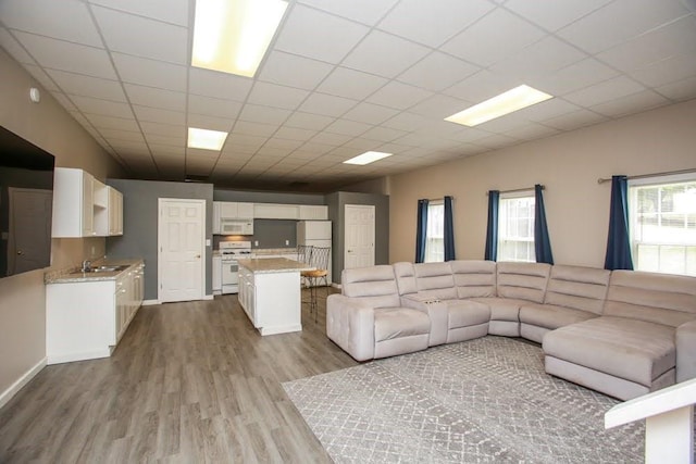 living area featuring dark wood finished floors, a drop ceiling, and baseboards