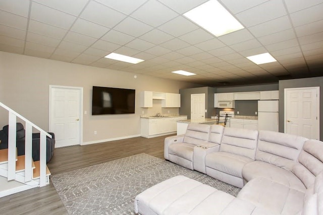 living room with wood finished floors, baseboards, and a drop ceiling