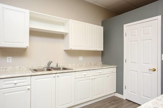 kitchen with a sink, white cabinetry, wood finished floors, and open shelves