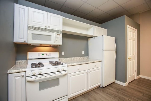kitchen featuring white appliances, wood finished floors, white cabinetry, and baseboards