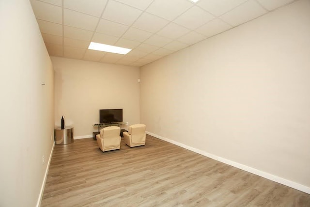 unfurnished room featuring light wood-type flooring, baseboards, and a paneled ceiling
