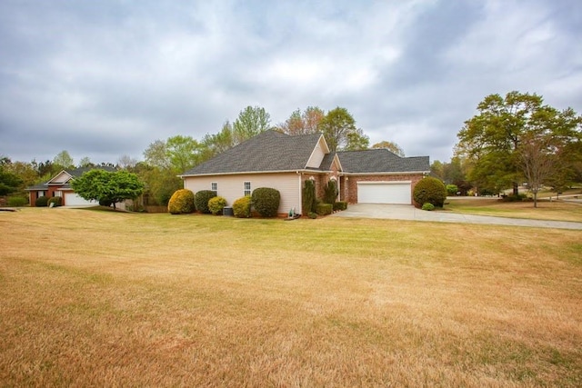 view of side of property featuring concrete driveway, an attached garage, and a lawn