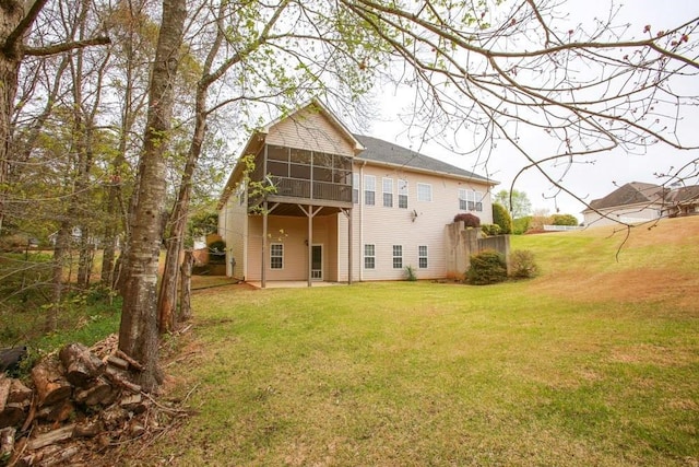 back of property with a sunroom, a yard, and a patio area