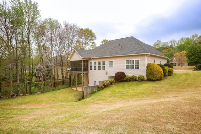 back of property with a sunroom, a lawn, and a shingled roof
