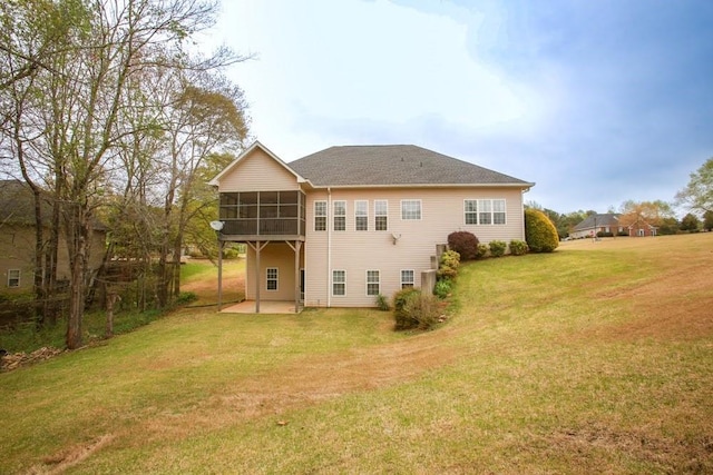 rear view of house featuring a sunroom, a patio, and a lawn
