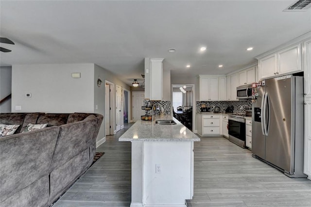 kitchen featuring appliances with stainless steel finishes, light stone counters, ceiling fan, sink, and white cabinets