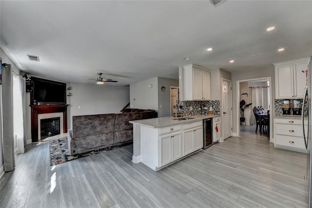 kitchen featuring backsplash, sink, white cabinets, and beverage cooler