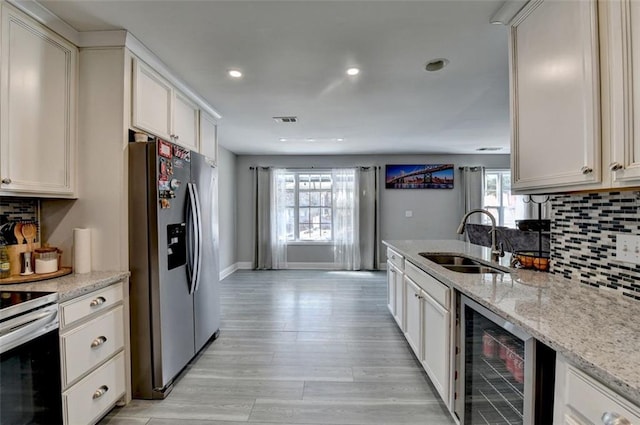 kitchen featuring range with electric cooktop, light stone counters, sink, stainless steel fridge with ice dispenser, and wine cooler