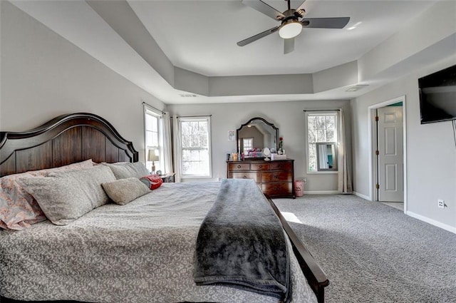 bedroom with multiple windows, carpet floors, a tray ceiling, and ceiling fan