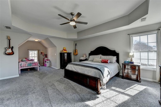 carpeted bedroom with ceiling fan, a tray ceiling, and multiple windows