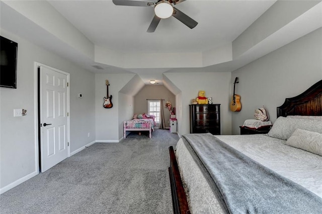 carpeted bedroom with a raised ceiling and ceiling fan