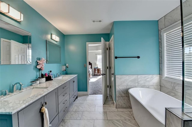 bathroom with vanity, a tub to relax in, and tile walls