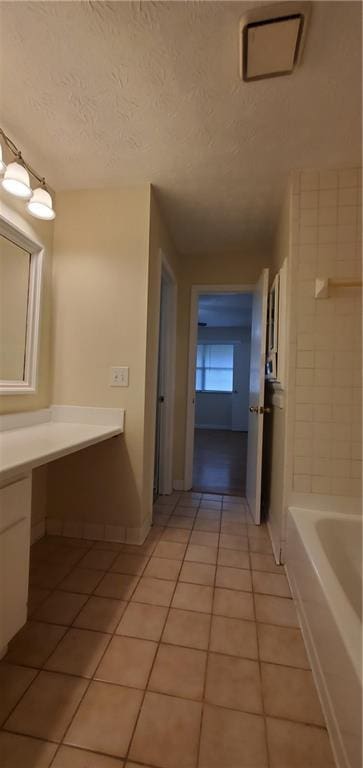 full bathroom with baseboards, a bath, tile patterned floors, a textured ceiling, and vanity