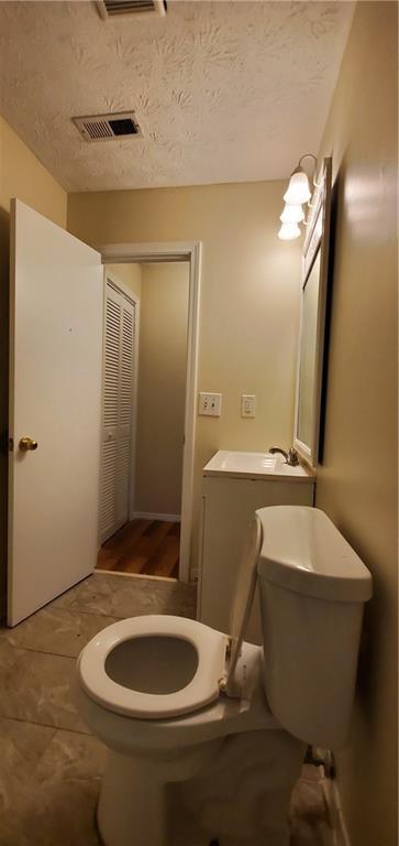 bathroom with visible vents, toilet, and a textured ceiling