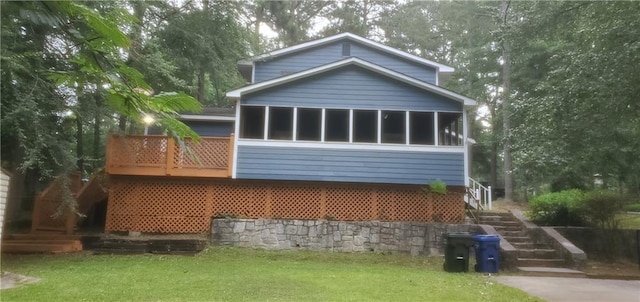 back of house with a lawn, a wooden deck, stairs, and a sunroom