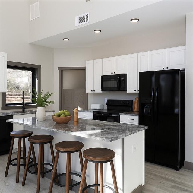 221 Dragonfly Cv, Toccoa, GA 30577 - kitchen with black appliances, white cabinetry, light wood-style floors, a breakfast bar area, and recessed lighting