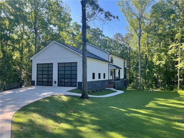 view of side of property featuring stone siding, concrete driveway, a yard, and an attached garage