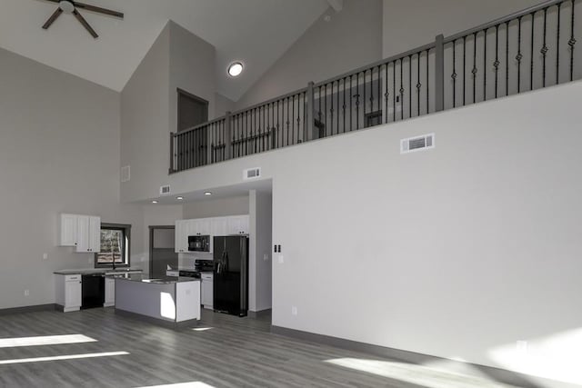 unfurnished living room featuring ceiling fan, dark wood-type flooring, and high vaulted ceiling