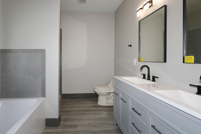 bathroom featuring a bathing tub, hardwood / wood-style floors, vanity, and toilet