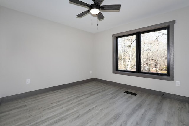 spare room with ceiling fan, wood finished floors, visible vents, and baseboards