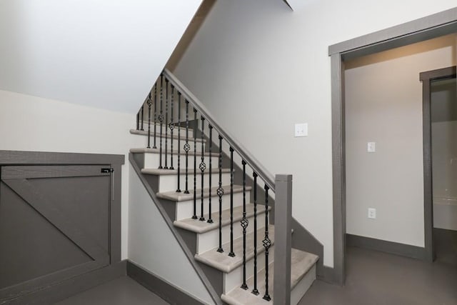 stairway featuring concrete floors and baseboards