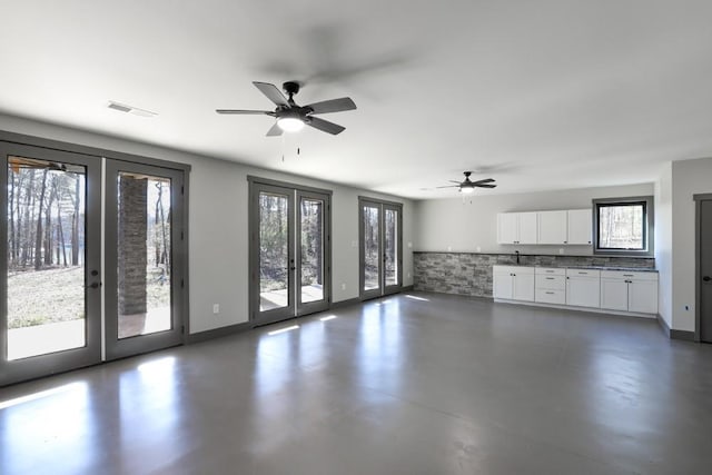 unfurnished living room with ceiling fan, a healthy amount of sunlight, and french doors