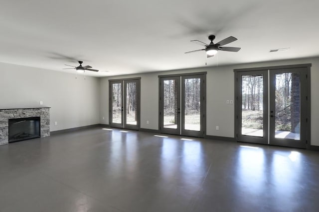 unfurnished living room with plenty of natural light, ceiling fan, a fireplace, and french doors