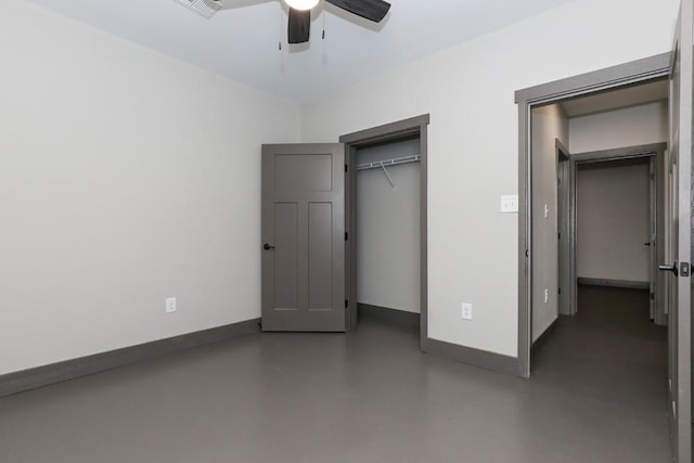 unfurnished bedroom with concrete flooring, ceiling fan, a closet, and baseboards