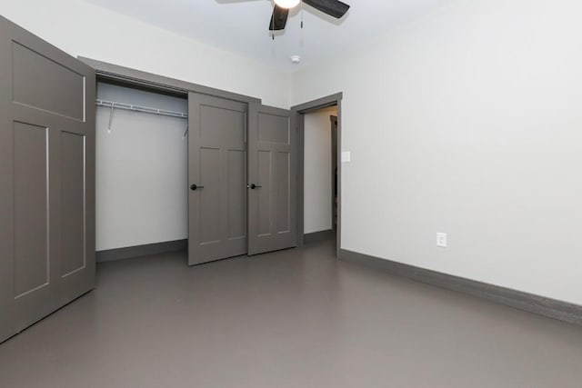 unfurnished bedroom with finished concrete flooring, a closet, a ceiling fan, and baseboards