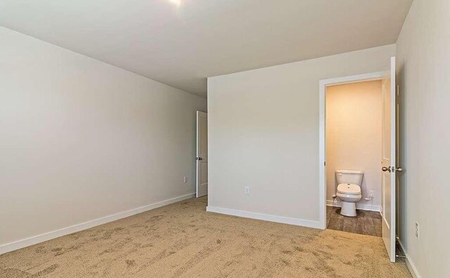 unfurnished bedroom with ensuite bathroom and carpet