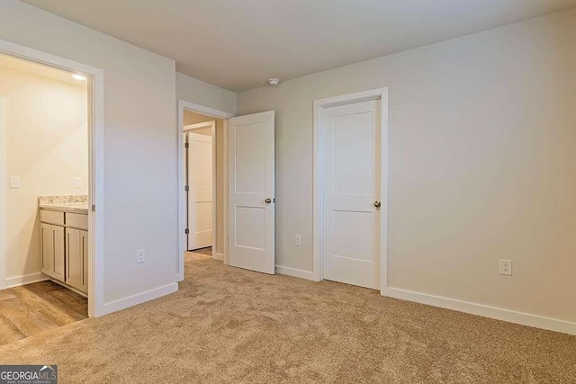 unfurnished bedroom featuring connected bathroom and light colored carpet