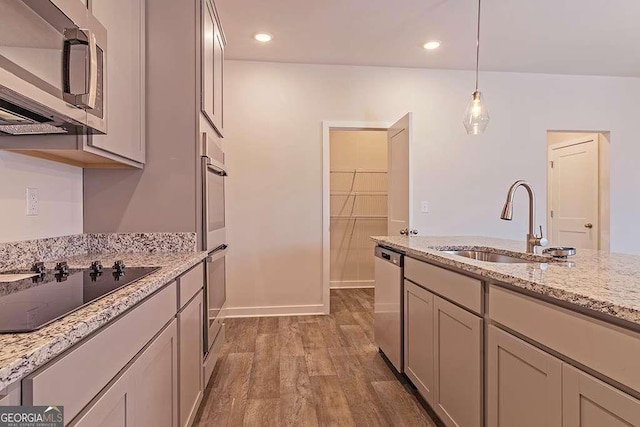 kitchen with pendant lighting, sink, light stone counters, stainless steel appliances, and dark wood-type flooring