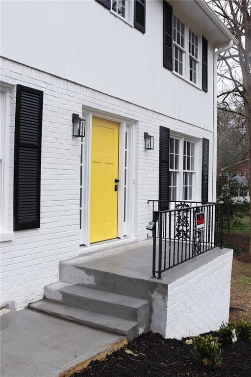 view of exterior entry featuring brick siding and covered porch