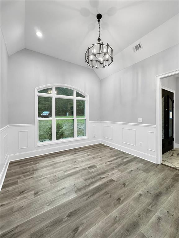 244 Coastline Rd, Fayetteville, GA 30214 - unfurnished dining area with lofted ceiling, a chandelier, wainscoting, wood finished floors, and a decorative wall