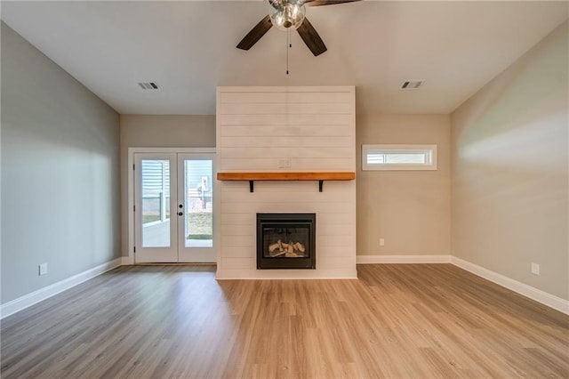 unfurnished living room with ceiling fan, a fireplace, and light hardwood / wood-style flooring