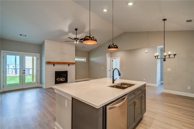 kitchen featuring a fireplace, sink, hanging light fixtures, stainless steel dishwasher, and a center island with sink