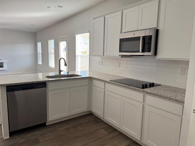 kitchen with dark wood-style floors, white cabinetry, stainless steel appliances, and a sink