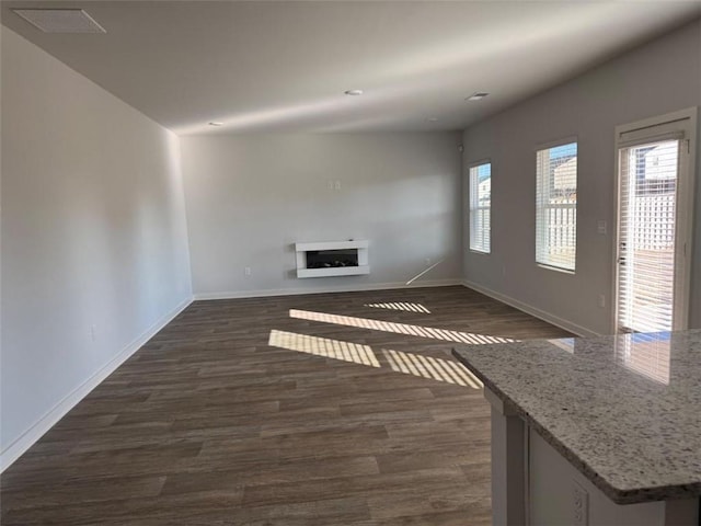 unfurnished living room with dark wood-style floors, a fireplace, and a wealth of natural light