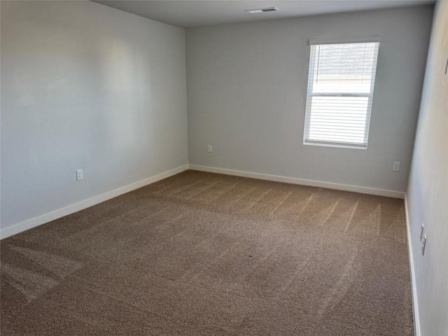 spare room featuring carpet flooring, visible vents, and baseboards