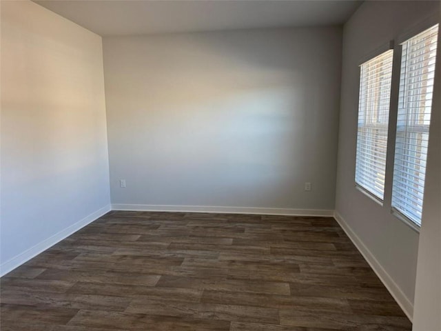 spare room featuring dark wood-style floors and baseboards