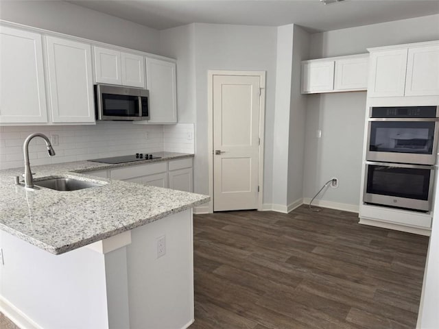 kitchen with stainless steel appliances, white cabinets, a sink, and a peninsula