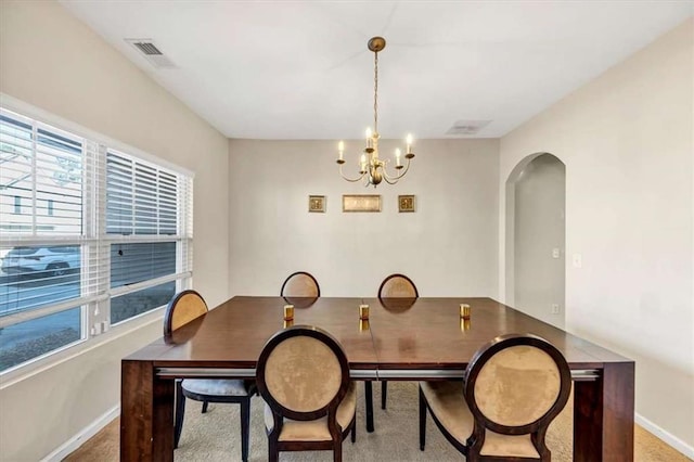 dining space featuring light colored carpet and an inviting chandelier