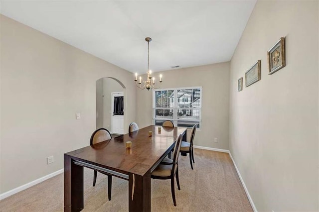 carpeted dining room featuring a notable chandelier