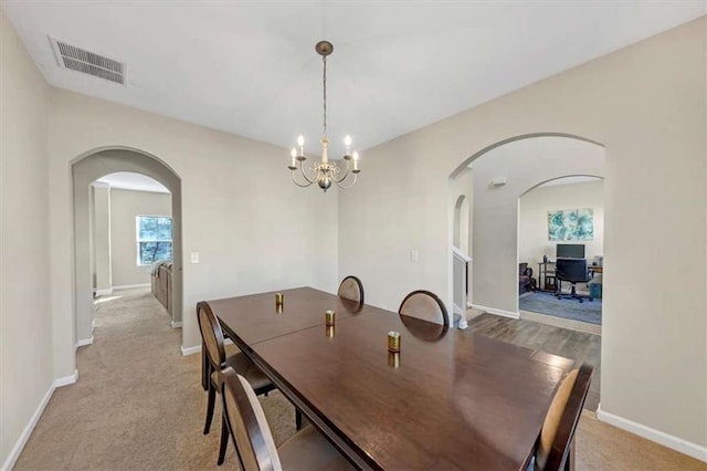 dining area with light colored carpet and a chandelier