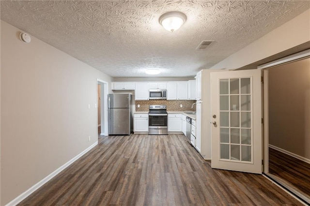 225 Fireside Way, Fairburn, GA 30213 - kitchen featuring stainless steel appliances, dark wood-style floors, light countertops, white cabinets, and a textured ceiling
